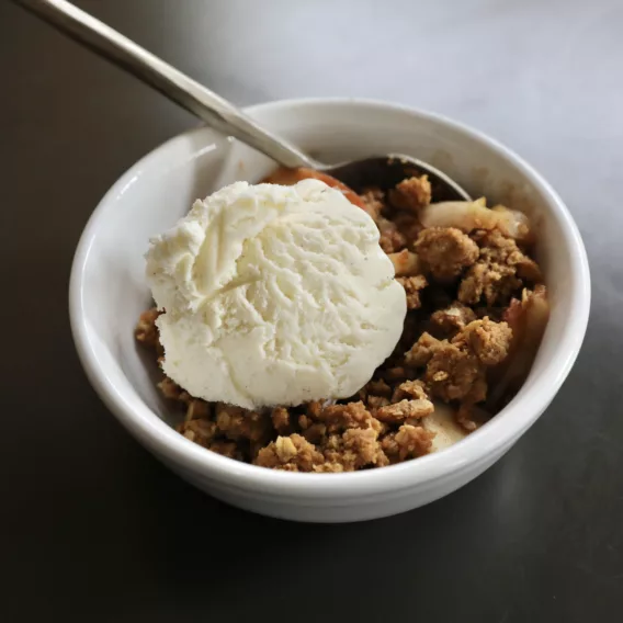 One serving of cookie butter apple crisp is topped with vanilla ice cream and ready to be enjoyed.