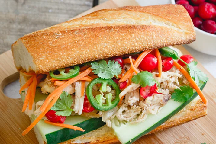 Turkey banh mi is shown from the side, loaded with toppings and ready to be eaten