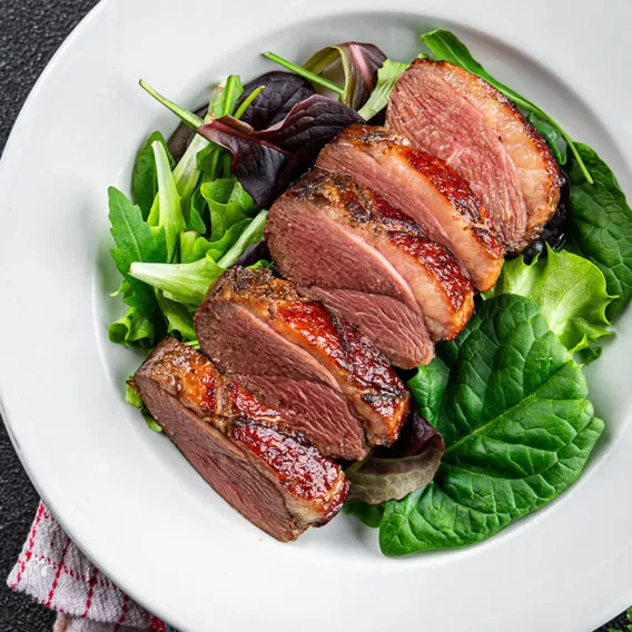 seared duck breast on a bed of greens