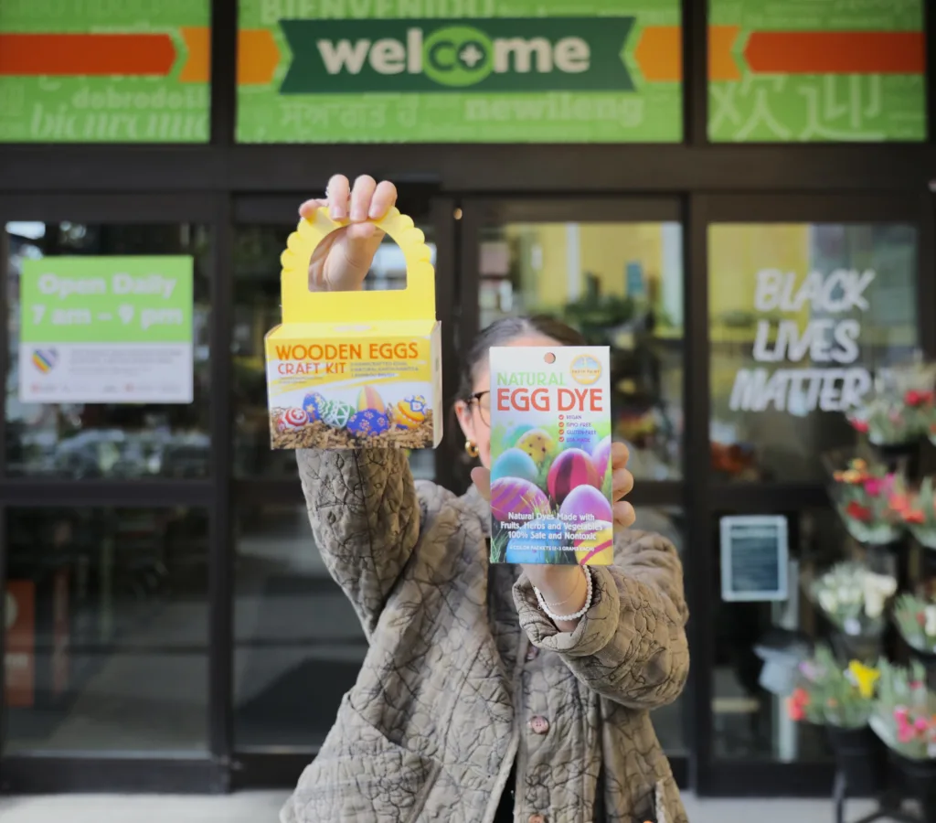 Someone holds an egg painting kit and an egg dye kit outside the Downtown store