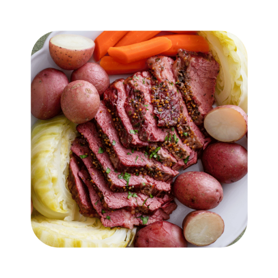 sliced corned beef surrounded by cabbage and roasted red potatoes