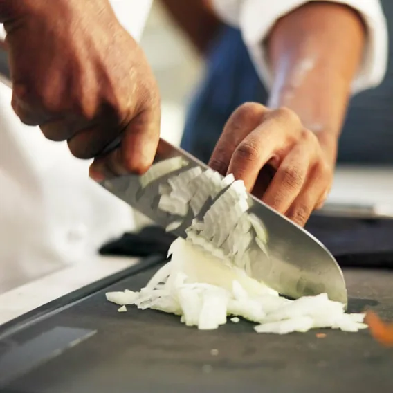 a chef demonstrates professional knife skills chopping an onion